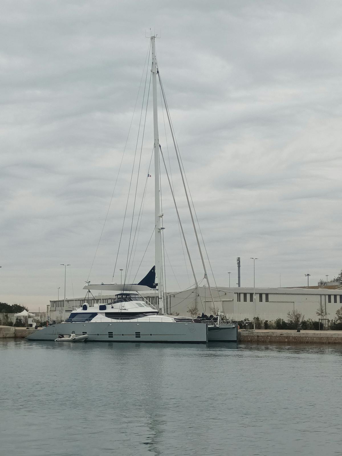 Catamaran moored at urban waterfront with cloudy skies