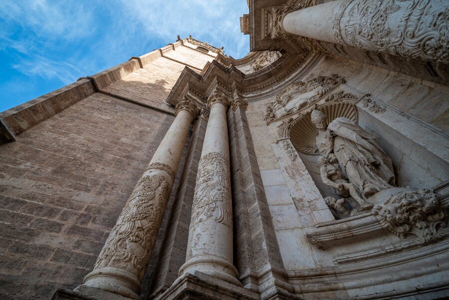 Intricate stonework on Valencia Cathedral facade under clear blue sky