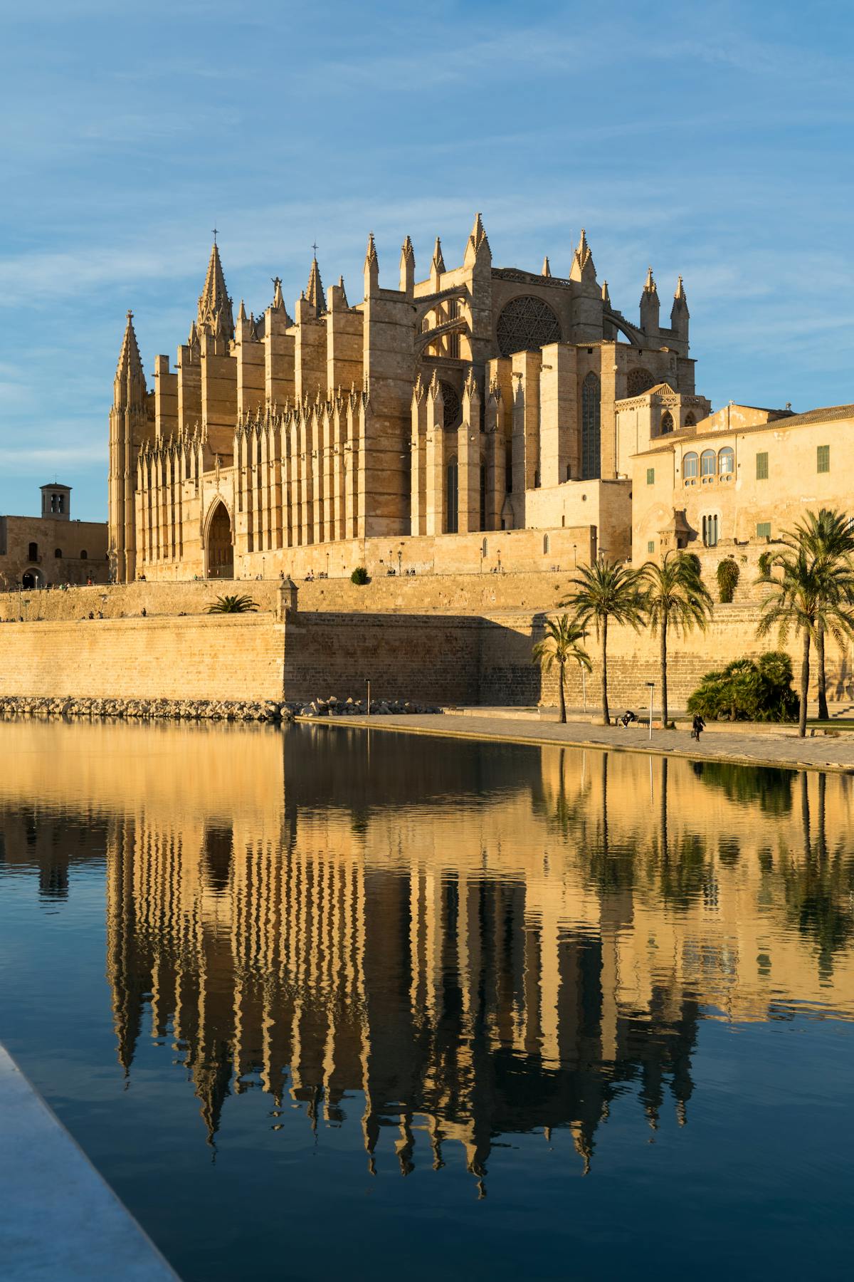 Gothic Palma Cathedral reflected in calm waterway during golden hour in Mallorca Spain