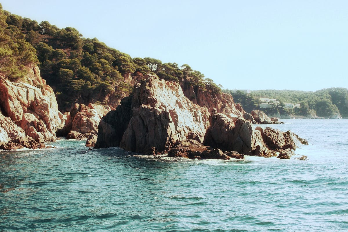 Dramatic rocky cliffs meeting azure sea in Costa Brava Spain