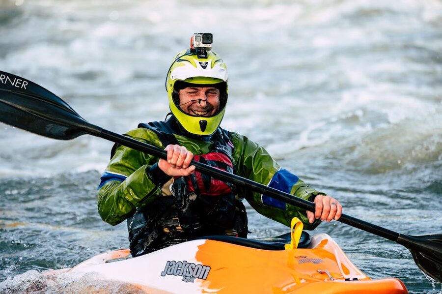 Man kayaking rapids helmet colorful gear