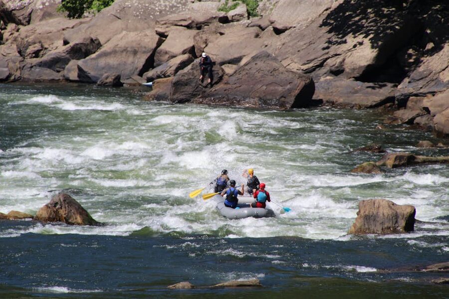 Adults whitewater rafting rocky rapids