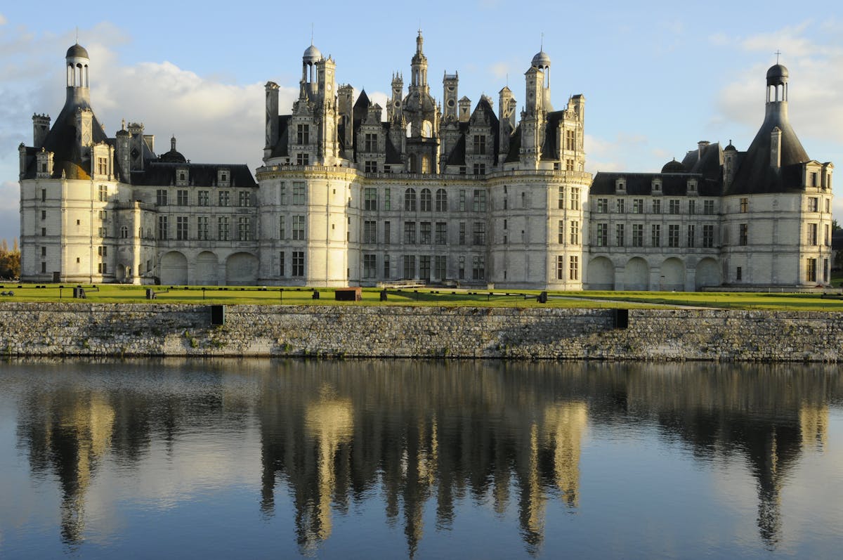 Chateau de Chambord reflected in calm waters of the canal