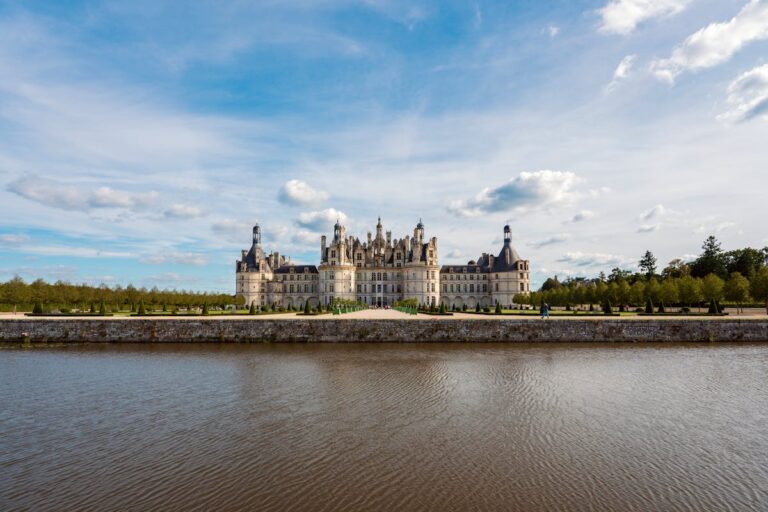 Chateau de Chambord with reflection in canal water under blue skies