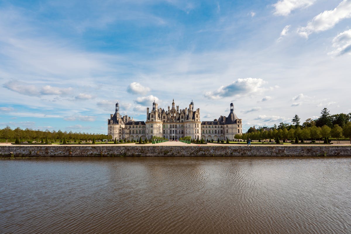 Chateau de Chambord with reflection in canal water under blue skies