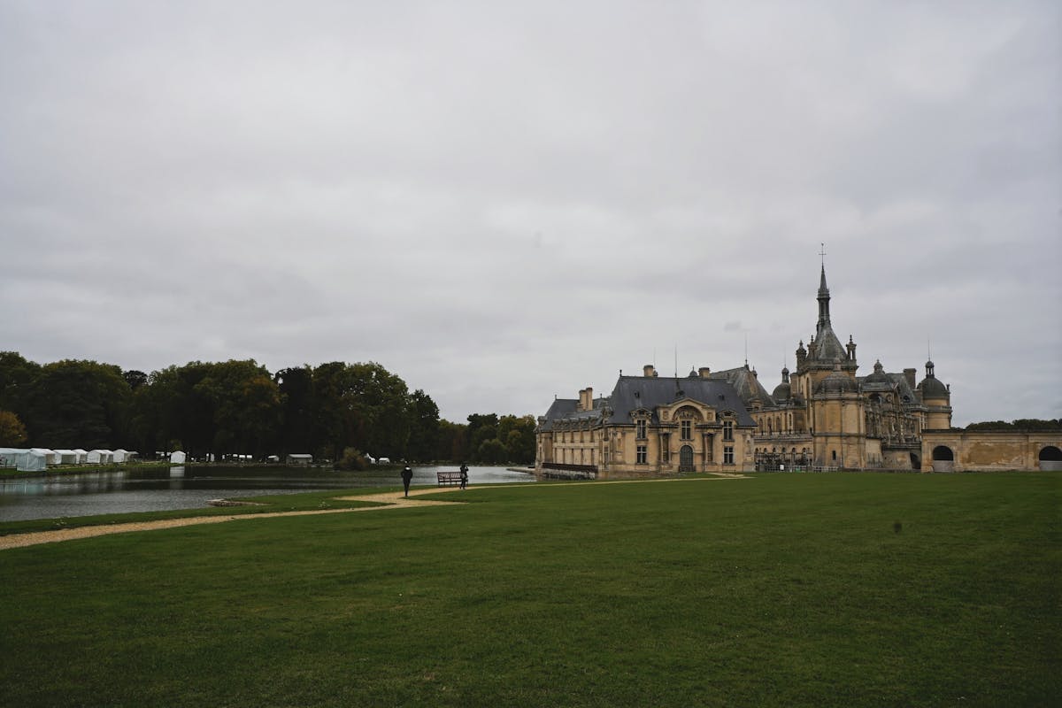 Chateau de Chantilly with lush greenery under overcast skies
