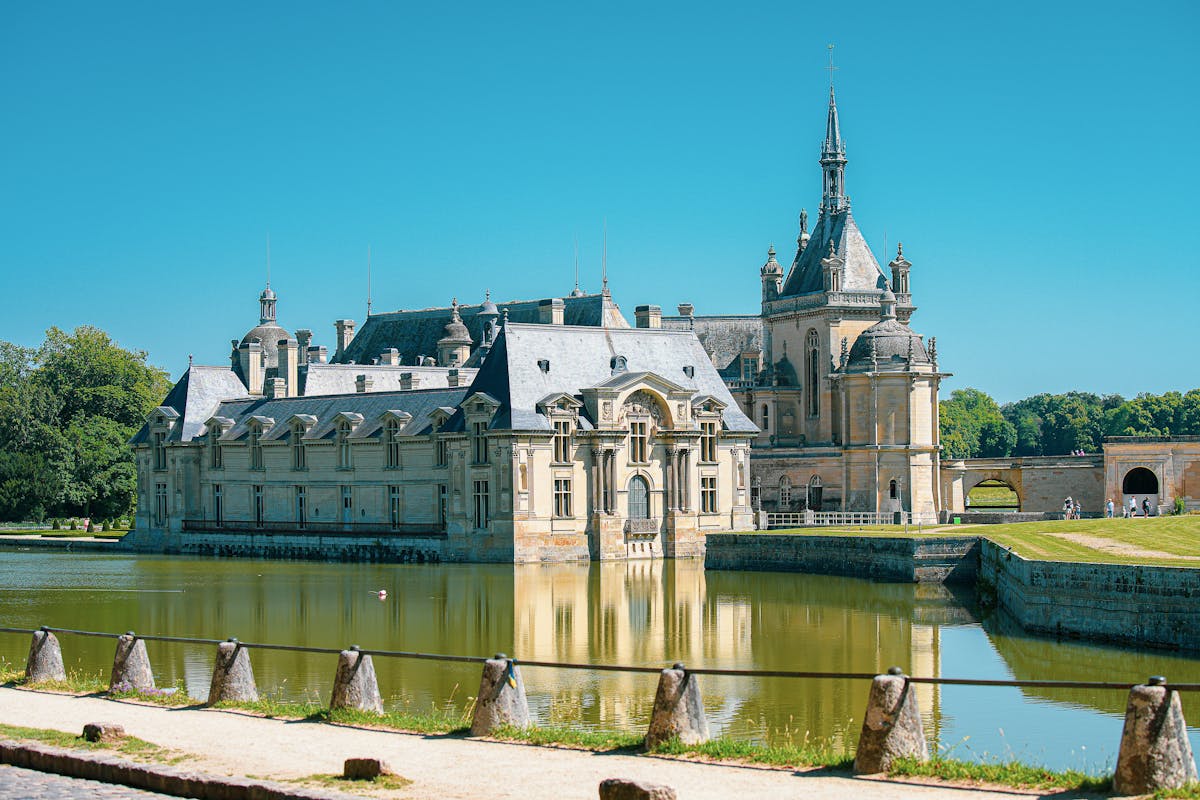 Chateau de Chantilly basking in summer sunlight with water reflection