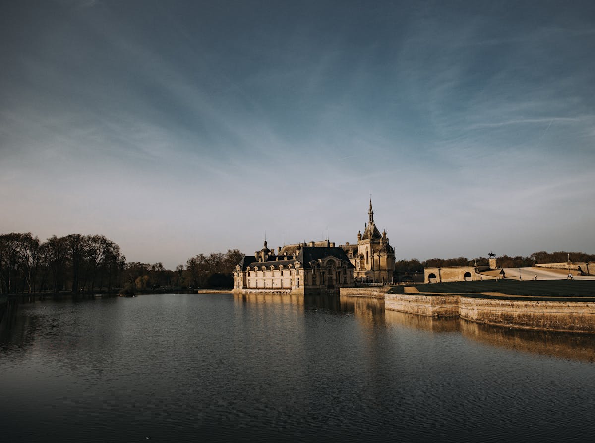 Chateau de Chantilly by tranquil waters under clear sky