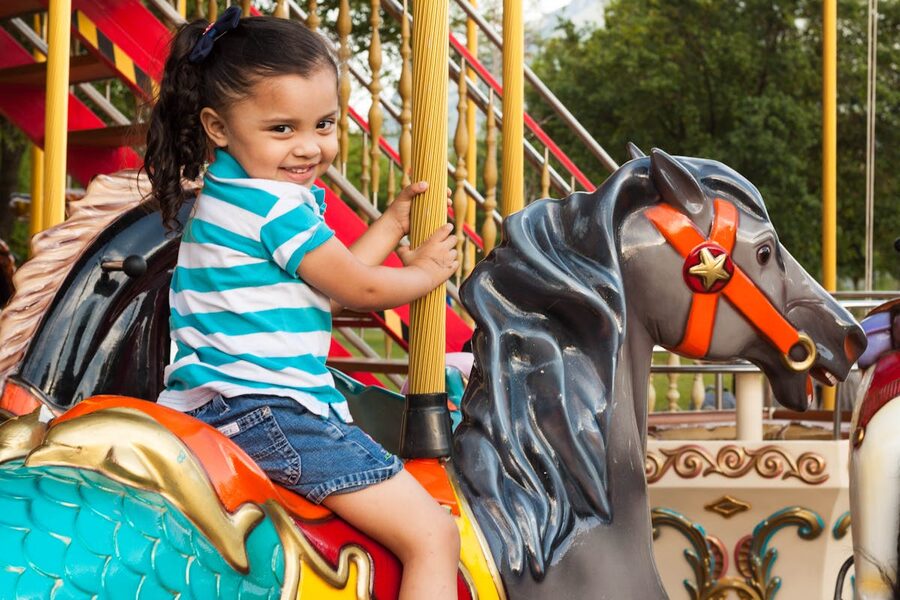 Happy child riding a colorful carousel at an amusement park