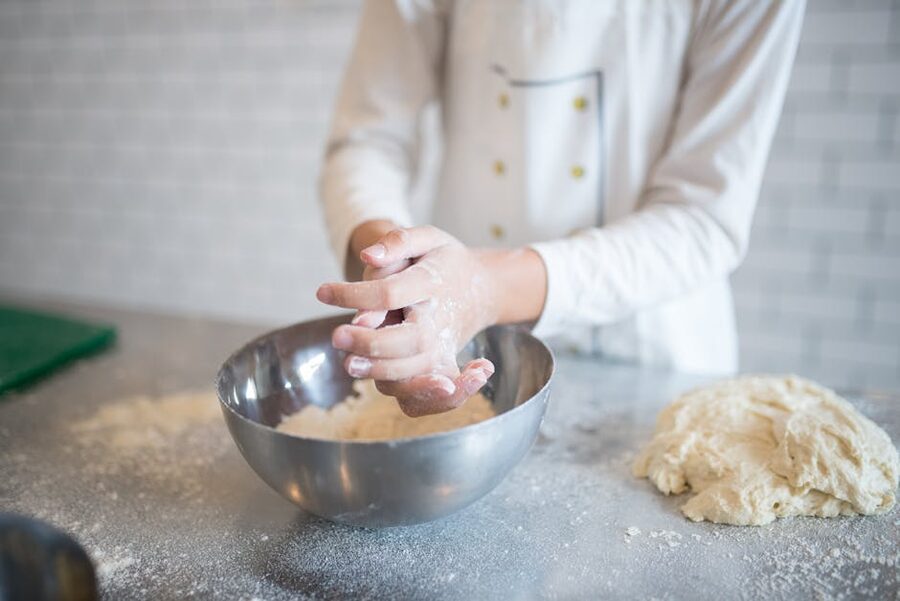 Hands kneading dough in a workshop kitchen