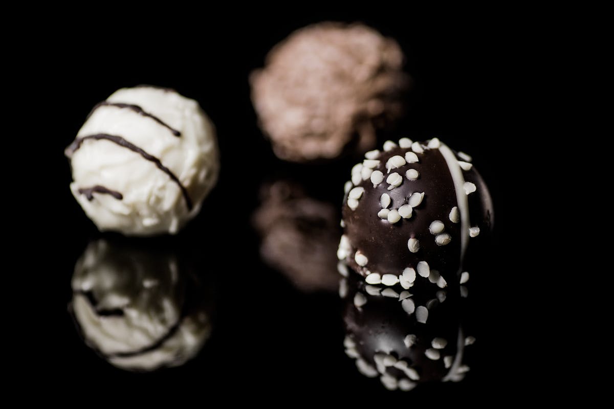Chocolate truffles with sprinkles on a reflective black surface