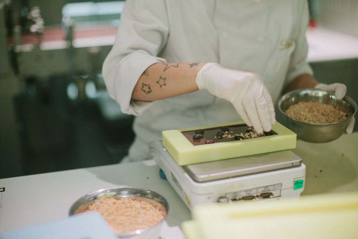 Close-up of a chocolatier adding toppings to a chocolate bar