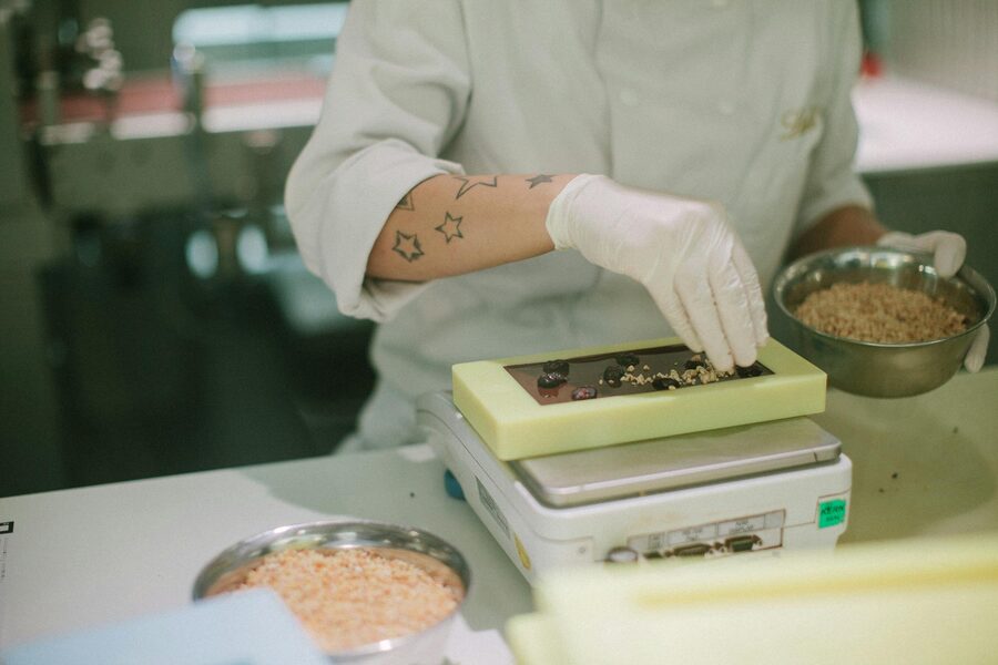 Chocolatier adding toppings to a chocolate bar