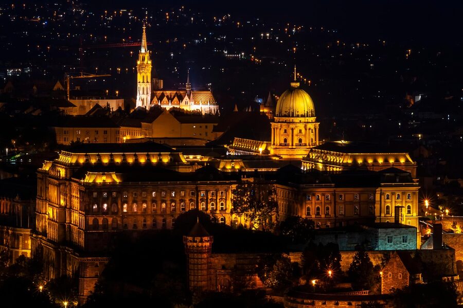 Buda Castle illuminated at night above the Danube