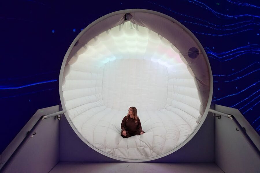 Person in a futuristic illuminated capsule installation