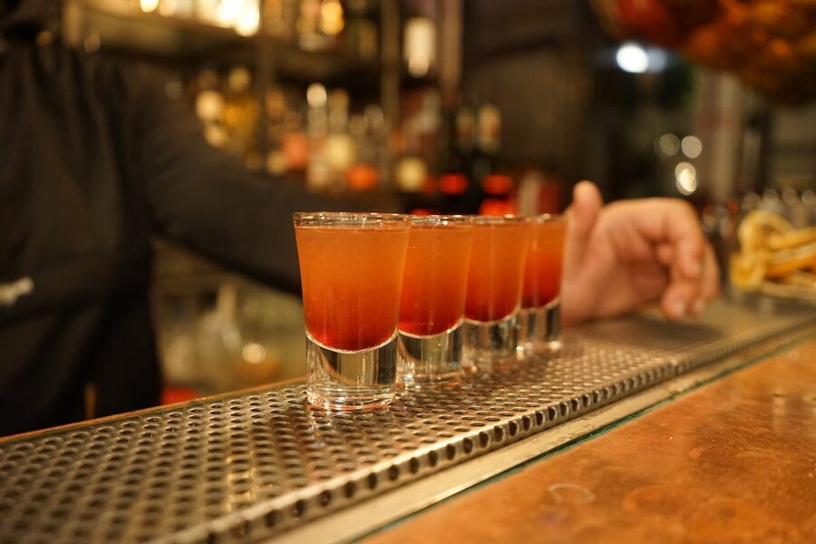 Colourful shot glasses lined up on a bar counter in nightlife setting