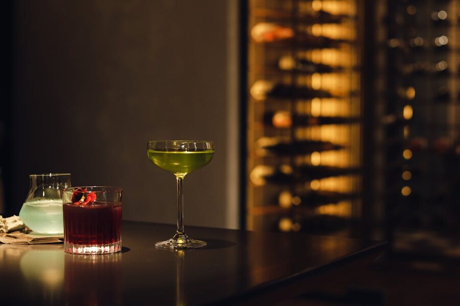 Colourful cocktails lined up on a dimly lit bar counter