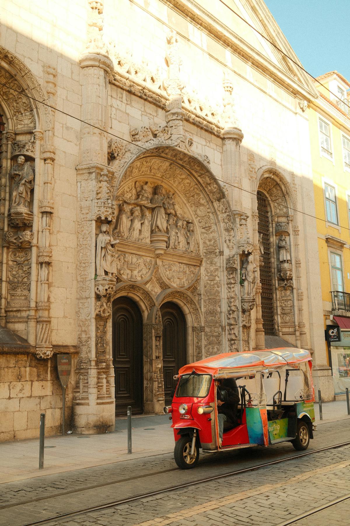 Colorful tuk-tuk parked in front of an ornate historic building in Lisbon