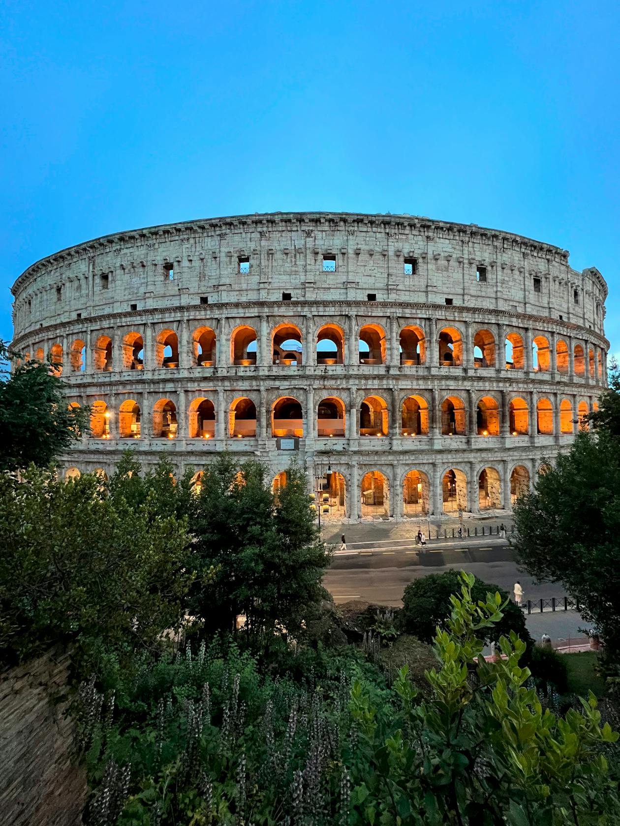 The Colosseum lit up at dusk with warm golden lighting