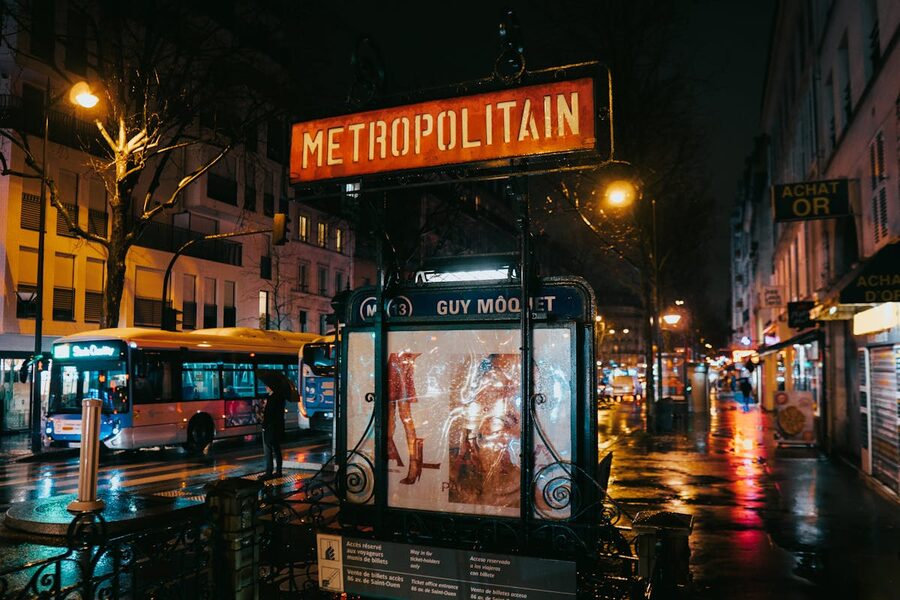 Paris metro entrance at night with glowing city lights