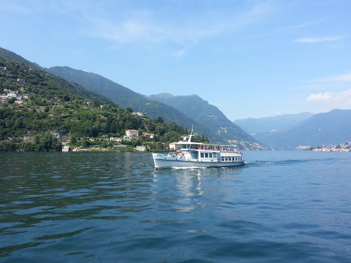 A ferry cruising on Lake Como surrounded by green hills
