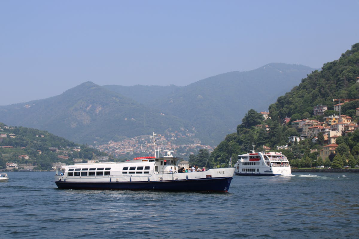 Passenger boats navigating the waters of Lake Como under clear skies