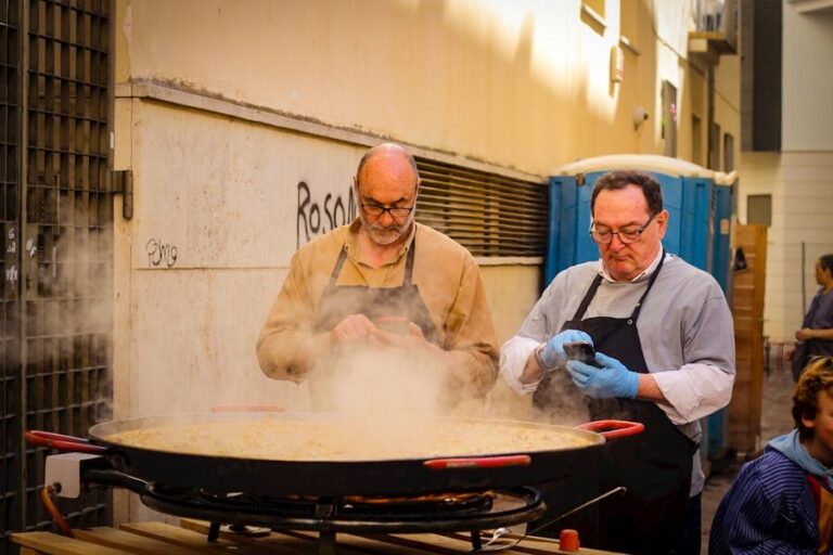 Two chefs preparing a large paella outdoors in Madrid