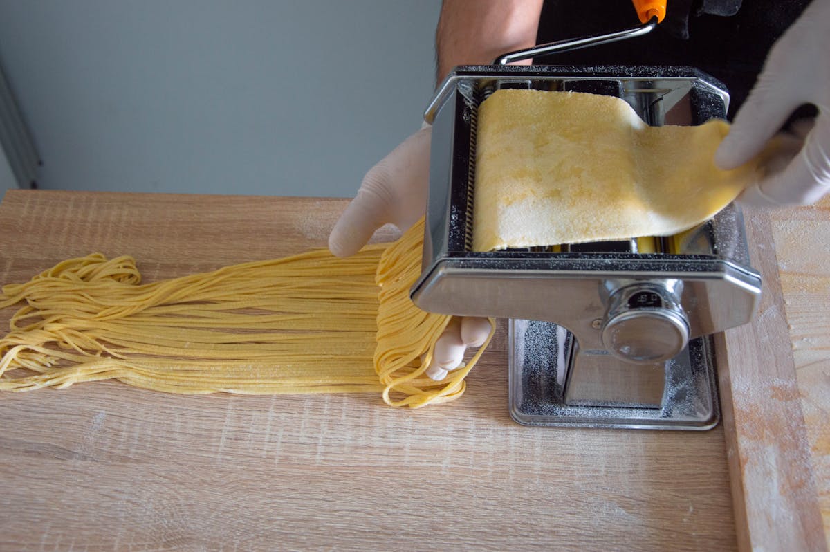 Fresh spaghetti being made with a traditional pasta maker in Rome