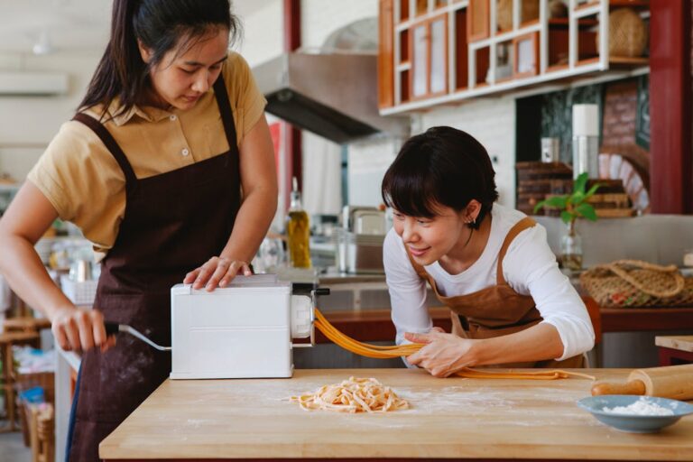 Two women using a pasta machine during a cooking class