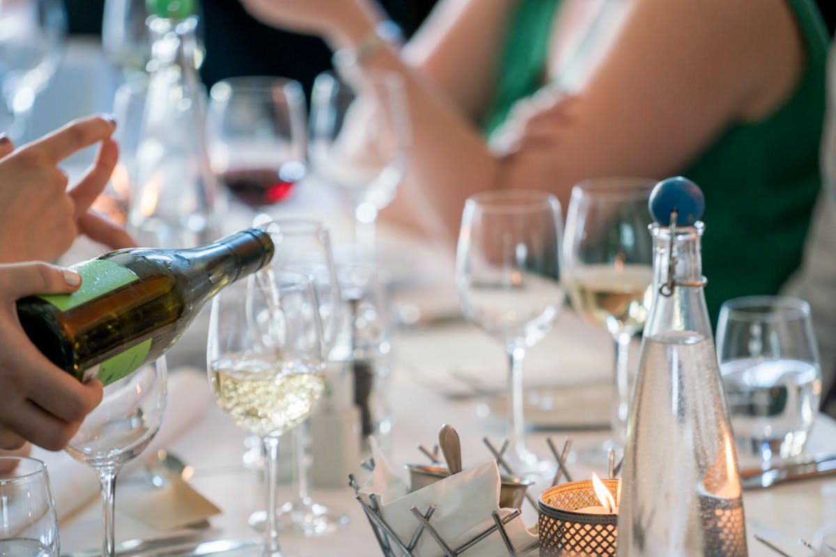 Wine being poured into a glass at an Italian dinner setting