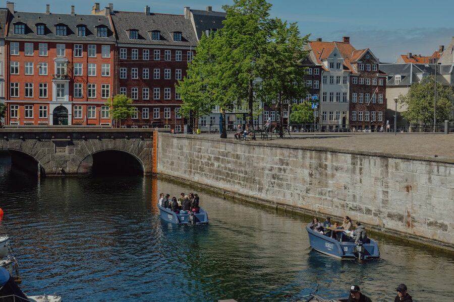 Canal boat tour with passengers passing colorful buildings in Copenhagen