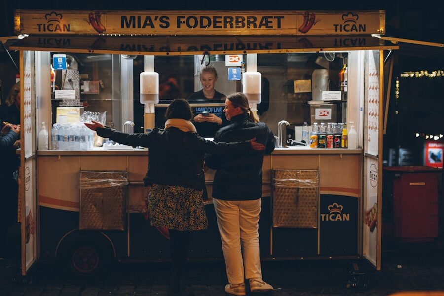 Women buying food at a Copenhagen street stand at night