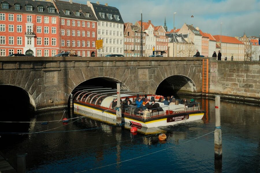 Canal boat with tourists passing under low bridge in Copenhagen