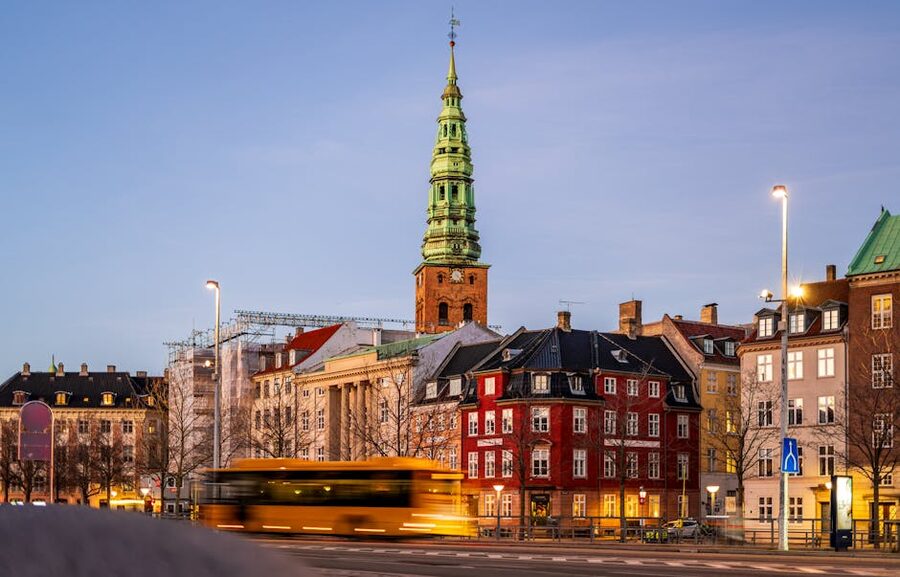 Copenhagen yellow city bus and historic buildings at dusk
