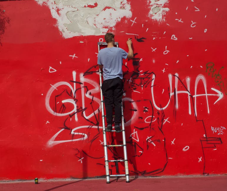 Street artist painting graffiti on a red wall in Copenhagen