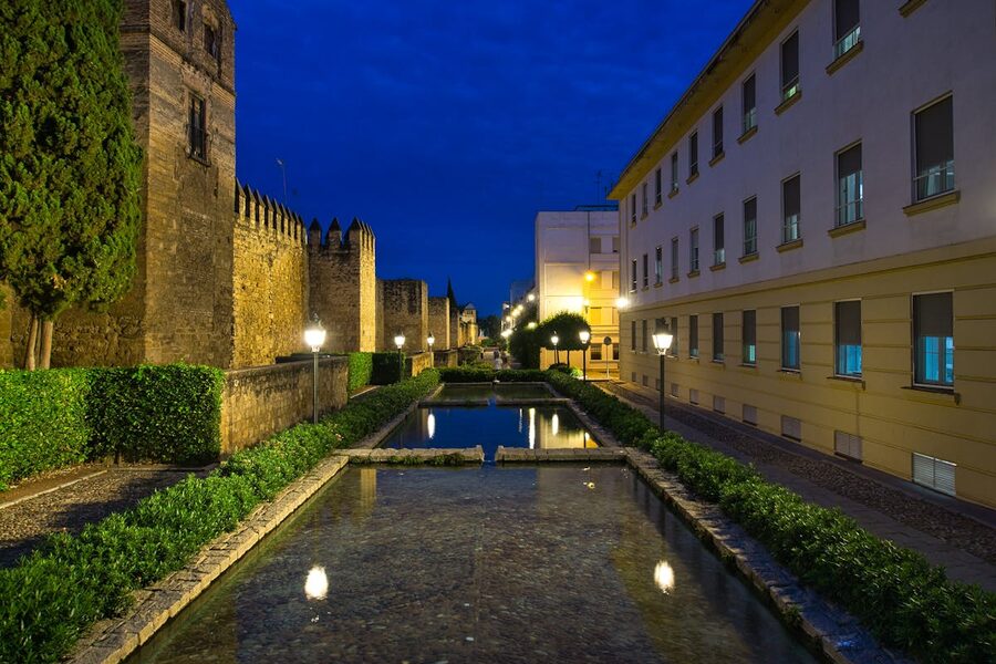 Illuminated historic walls of Cordoba at night with water reflections