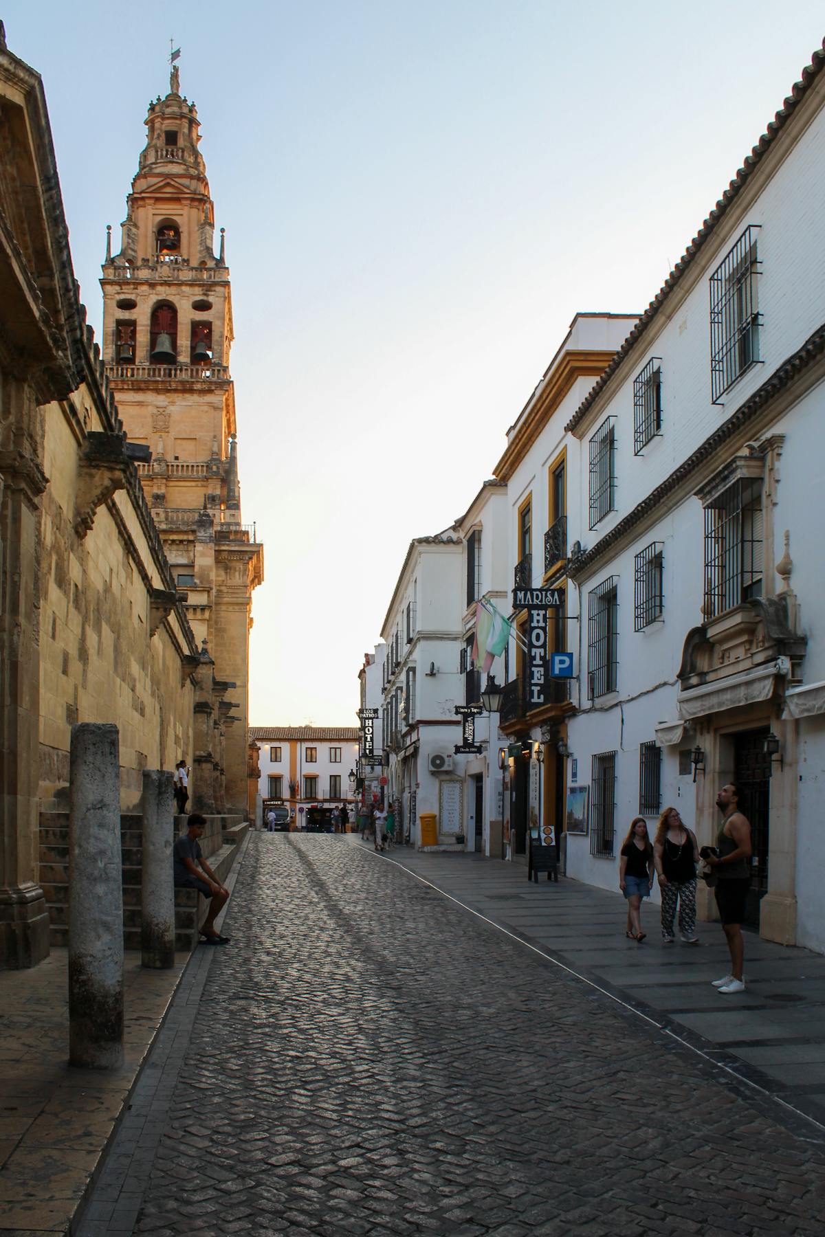 A charming narrow street in Cordoba old town with the Mosque-Cathedral tower visible at sunset