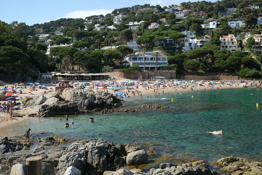Summer beach with turquoise waters and houses on Costa Brava