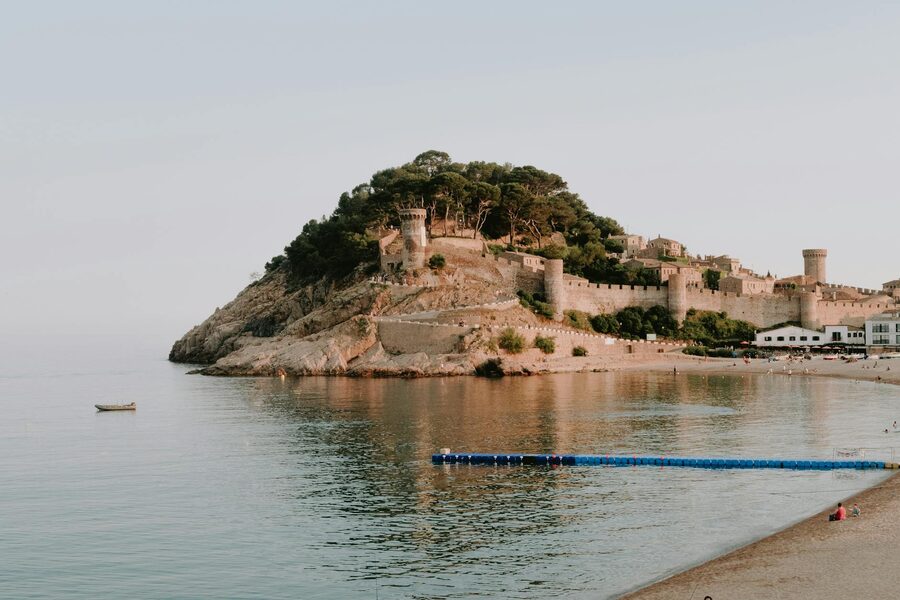 Medieval castle on the Costa Brava coast with calm sea and sandy beach