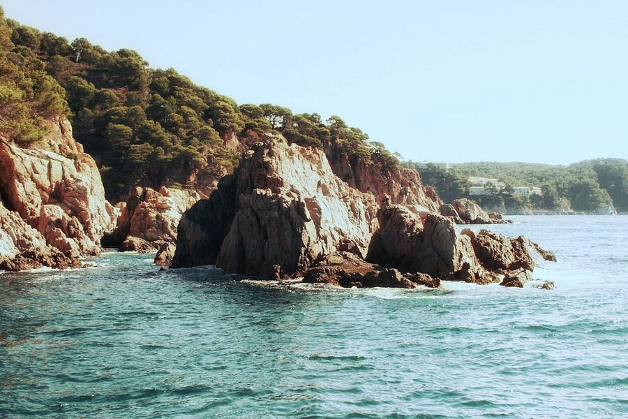 Dramatic rocky cliffs dropping into clear blue water along the Costa Brava coast of Catalonia