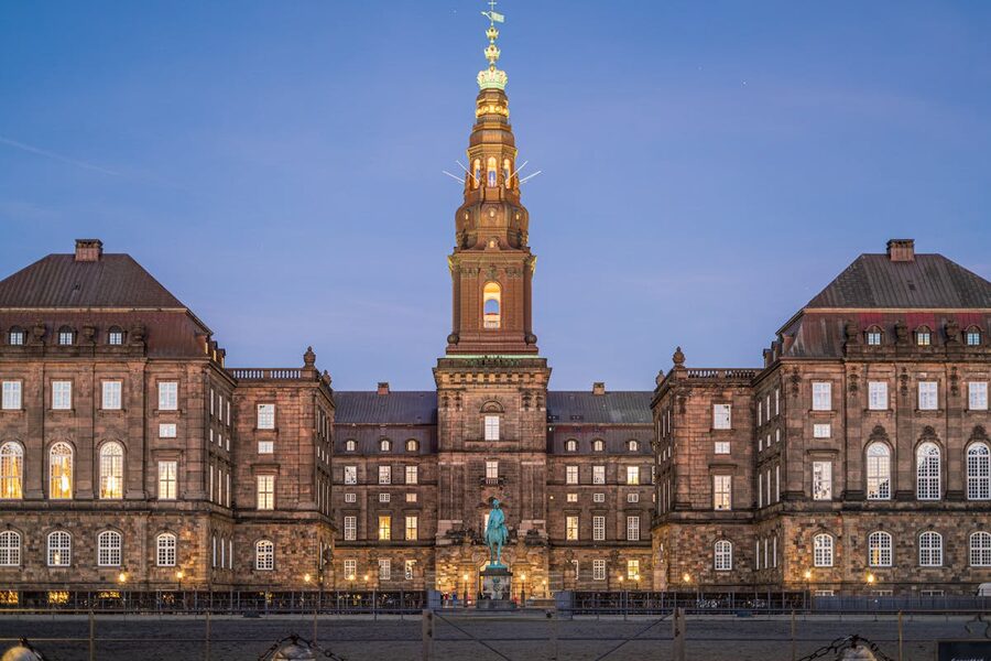 Christiansborg Palace with illuminated spire in the evening in Copenhagen Denmark