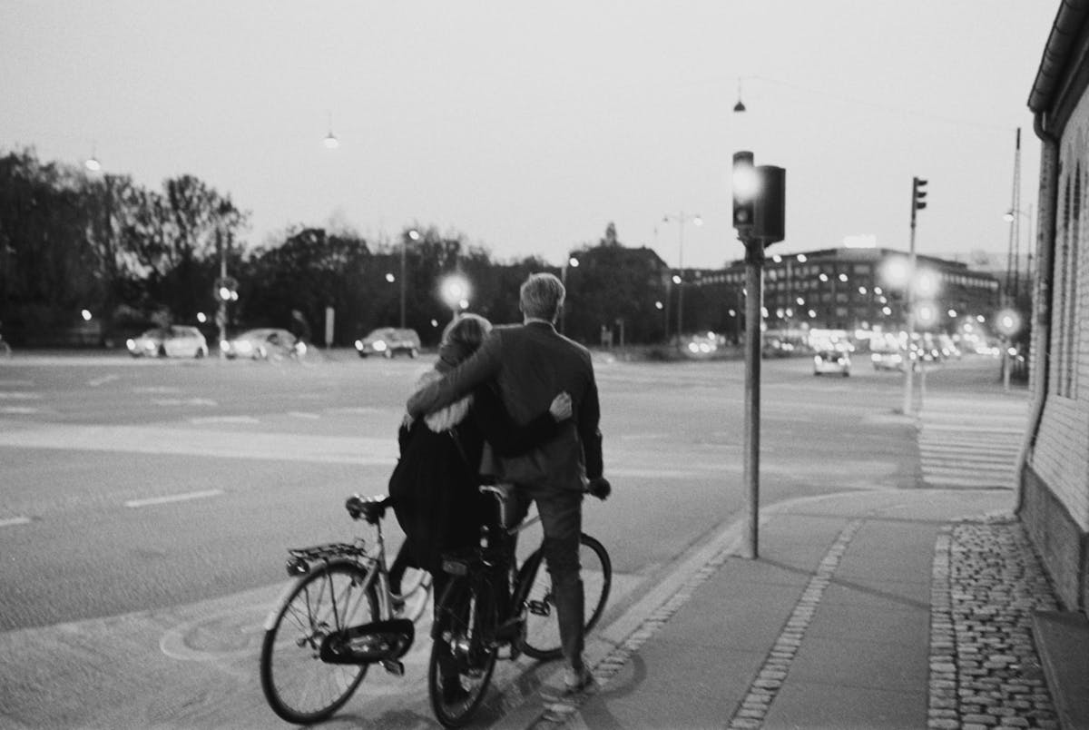 Couple on bicycles at a Copenhagen intersection during twilight