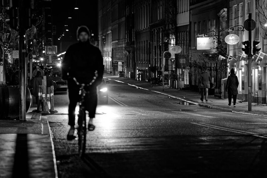 Cyclist riding through illuminated Copenhagen streets at night