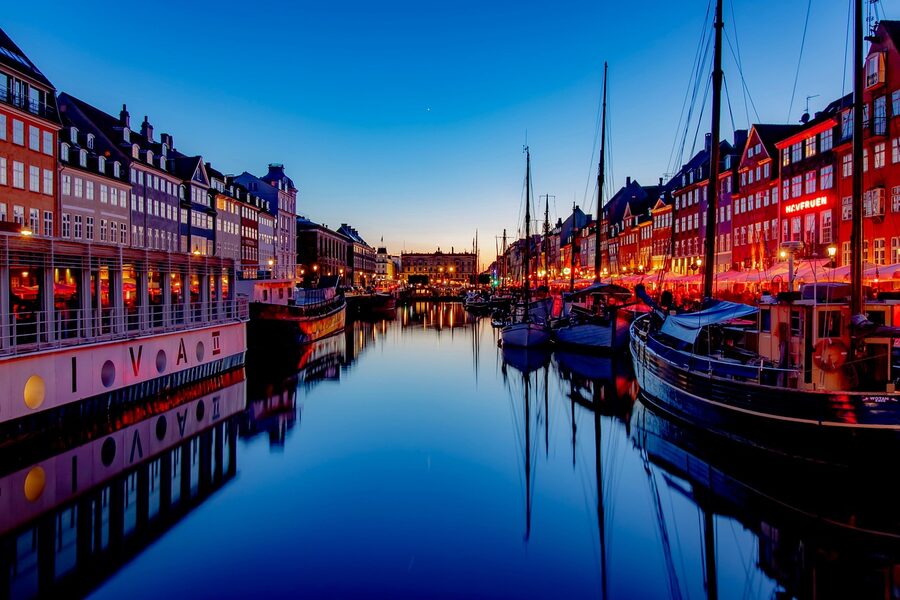 Copenhagen harbor at sunset with Nyhavn canal boats and warm light
