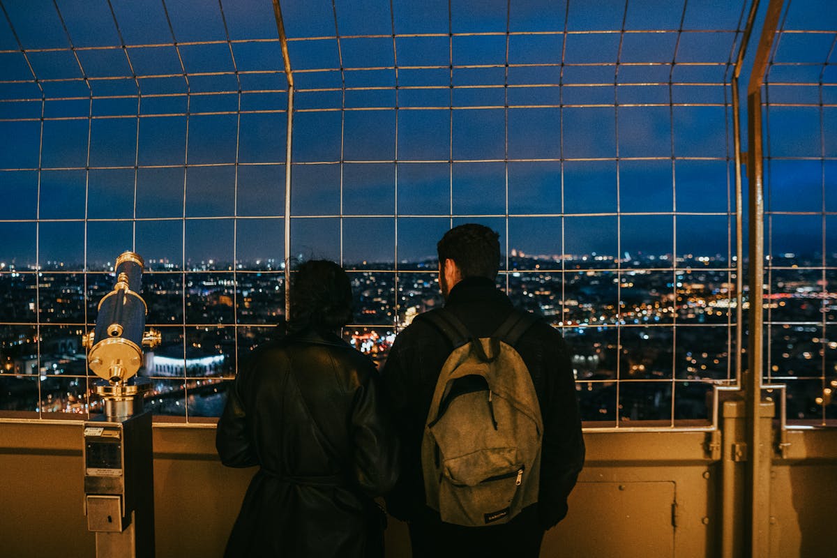 Couple enjoying a twilight view of Paris from a tower, capturing the city skyline