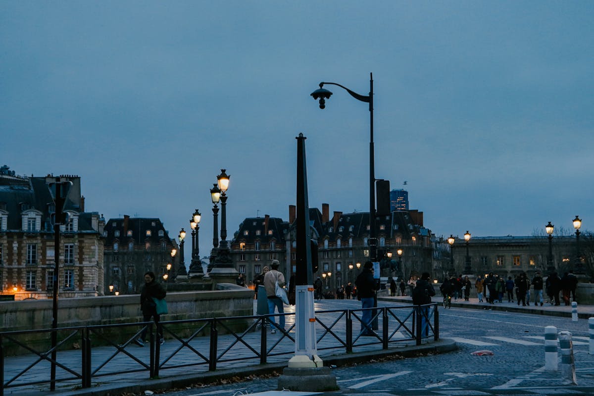 People walking on a Paris street in the evening under street lights