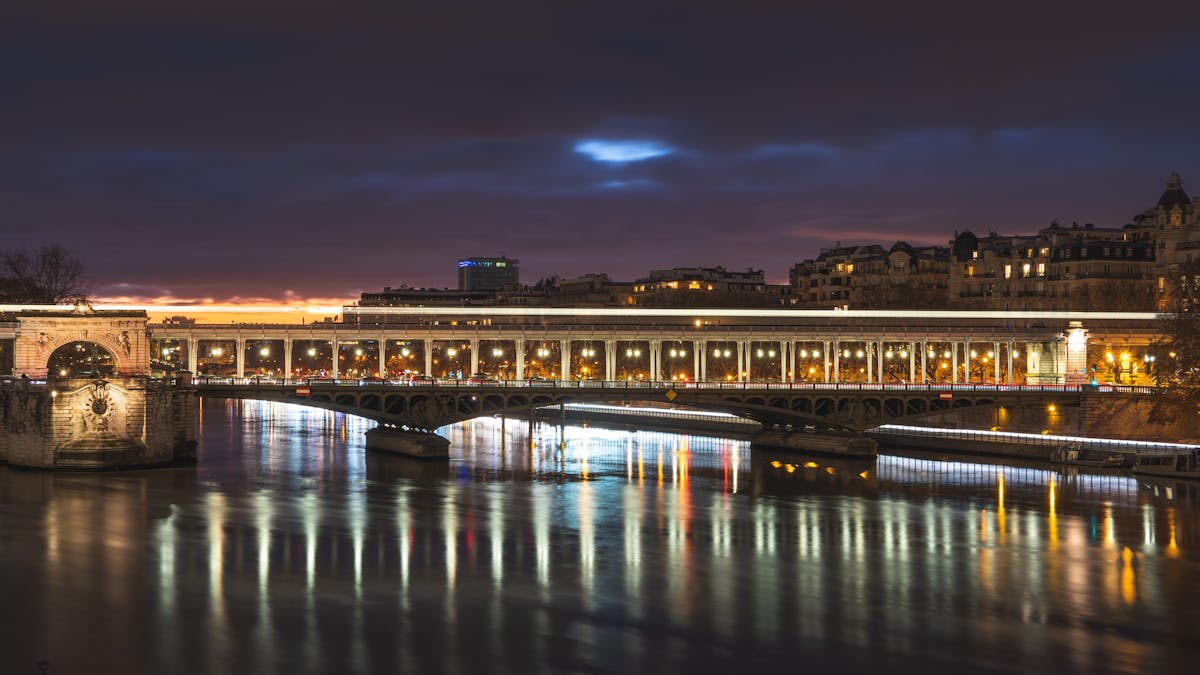 Nighttime view of a Paris bridge with reflections on the Seine
