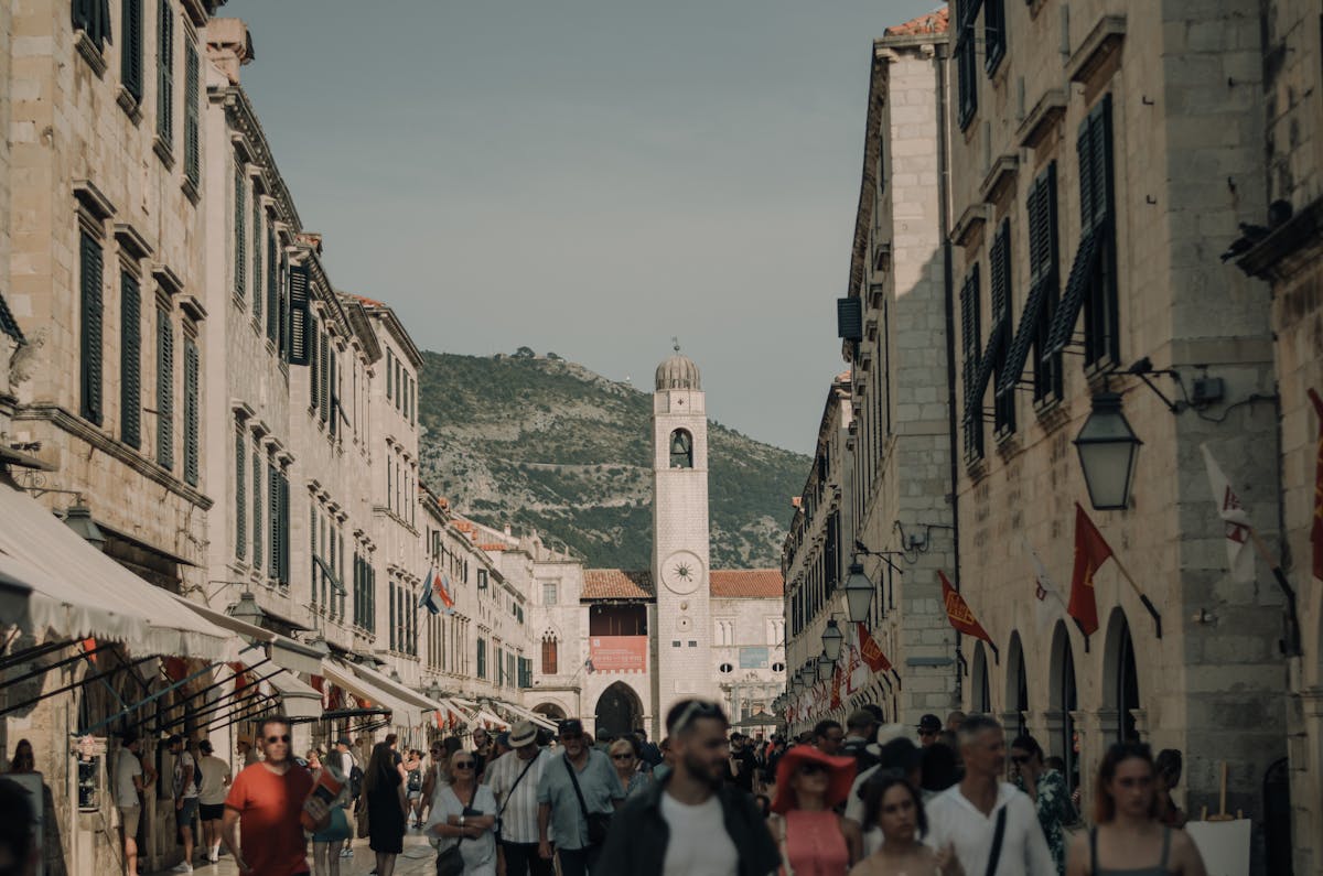Pedestrian street with clock tower and travelers in Dubrovnik old town