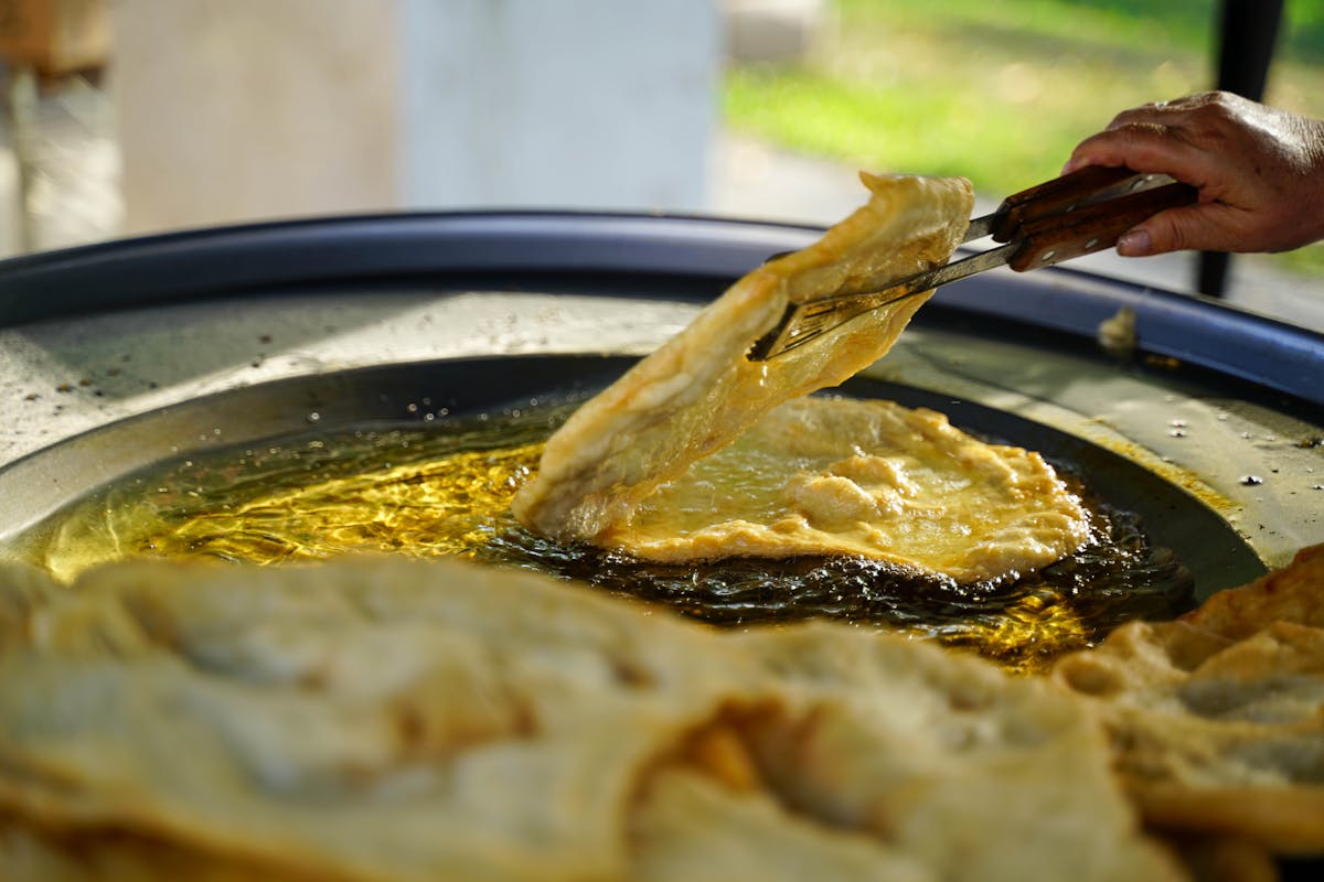 Hand frying traditional Croatian flatbread outdoors in olive oil