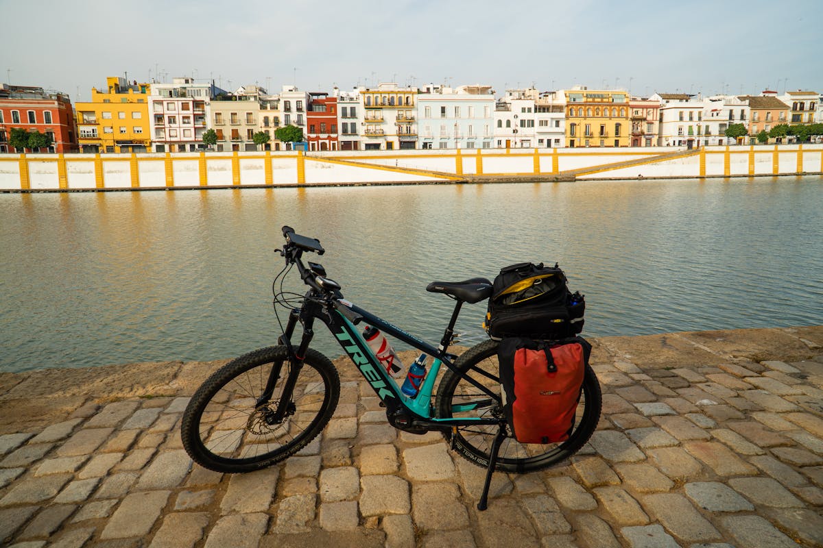 A bicycle parked by a riverbank in Seville Spain with a city skyline view under a clear sky
